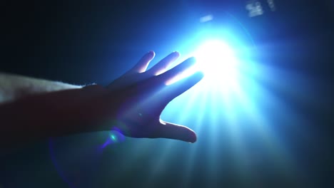 hand reaching out to cover shinning spot light