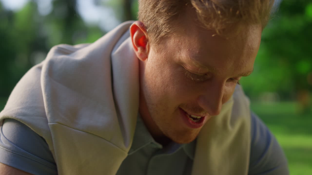 радостный парень разговаривает в парке. улыбающийся блондин играет неизвестного питомца.