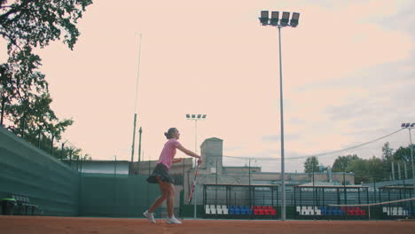 low angle view in slow-motion of a young female tennis player preparing to serve a tennis match. a woman athlete is powerfully hitting a ball during sports practice. commercial use footage