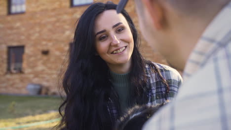 close-up view of caucasian couple squatitng and petting their dog in the countryside