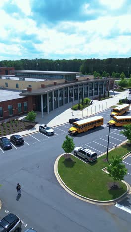 vertical - school buses and cars on parking lot of cobb innovation and technology academy in marietta, georgia. aerial shot