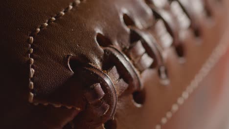 close up shot of person picking up american football with stars and stripes flag in background