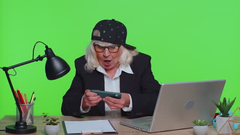 mujer de negocios senior preocupada se sienta en el lugar de trabajo evita trabajar, jugar carreras o videojuegos de disparos