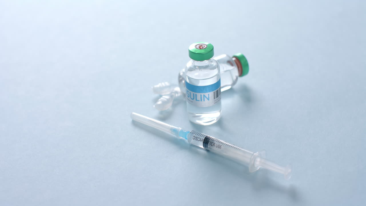 Close up of insulin vials and syringe on blue background with copy space, slow motion