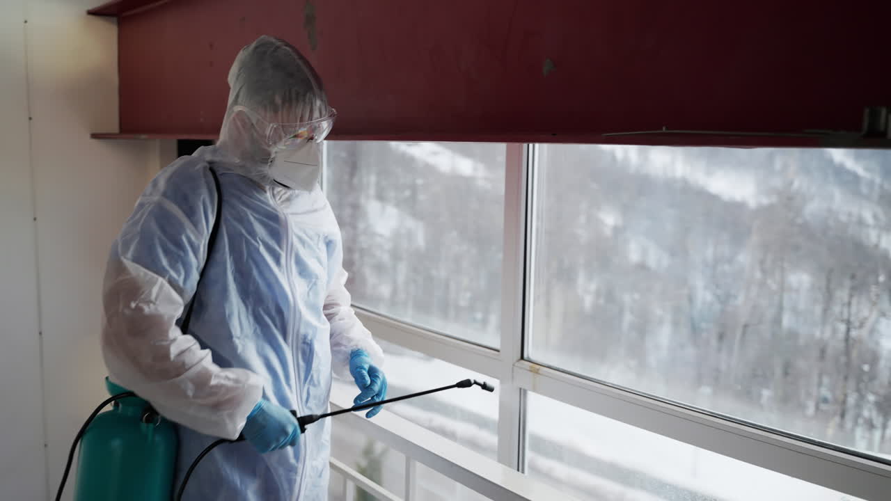 trabajador de desinfección rociando ventanas