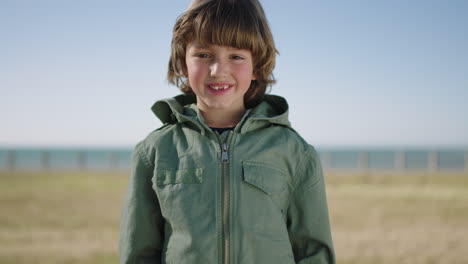 portrait of cute caucasian boy smiling cheerful at camera enjoying fun day on seaside beach park