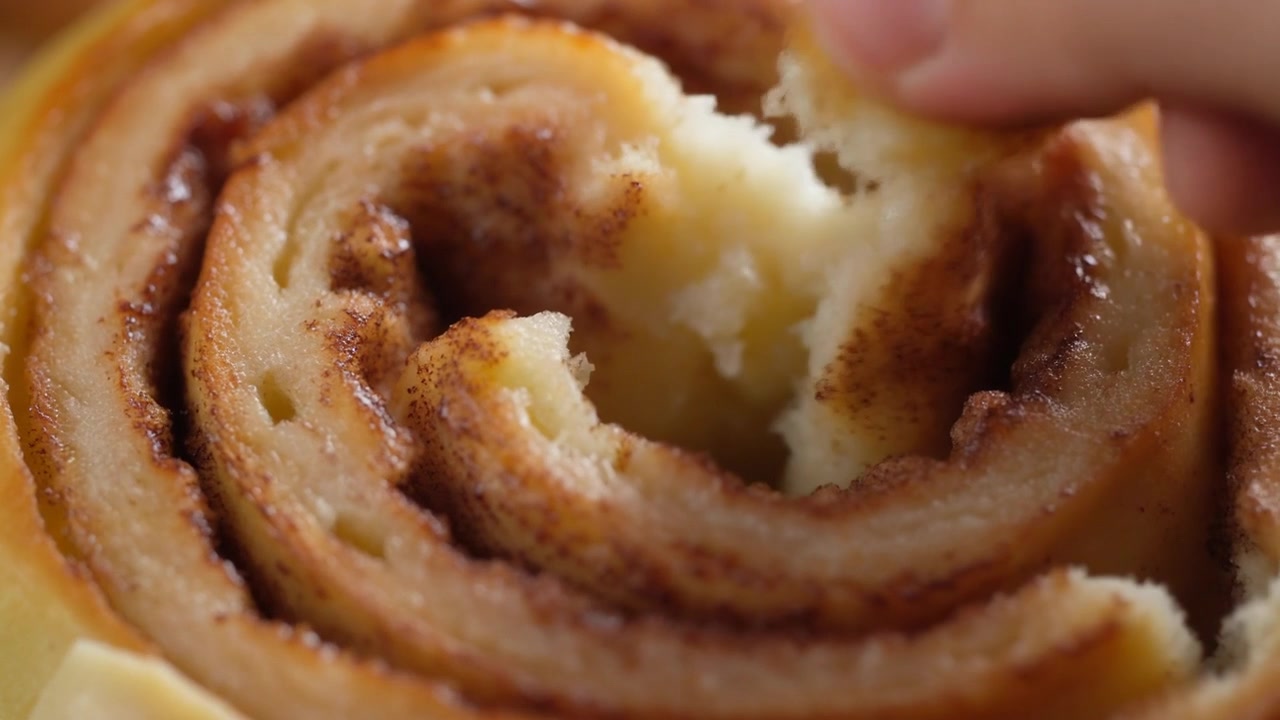 Mano che strappa un rotolo alla cannella fresco