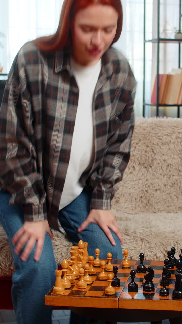 Woman on sofa playing chess against herself smiling having fun with playful split personality mood
