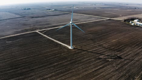 Aerial-view-approaching-a-solo-wind-turbine-on-rural-farmland