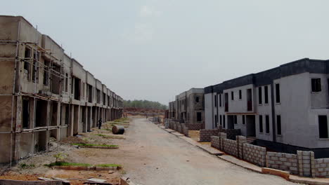 casas adosadas terminadas a la derecha y construcción inacabada a la izquierda en un sitio de proyecto en nigeria para construir mini propiedades
