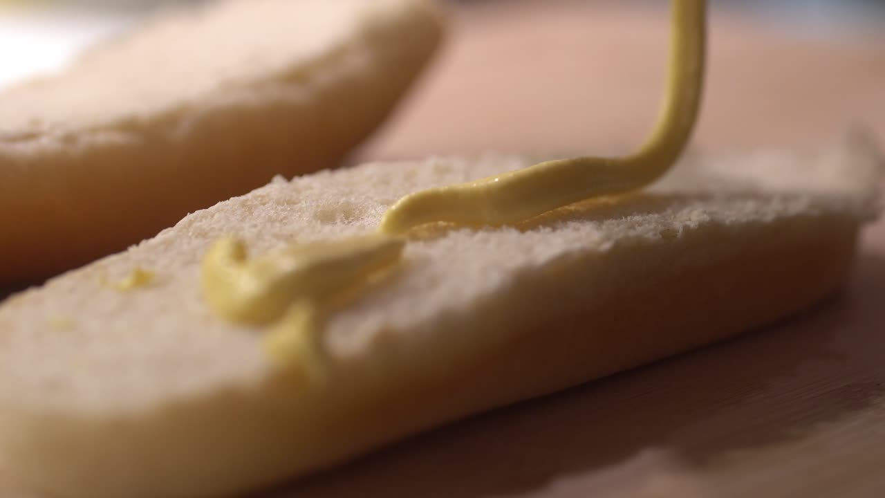 Closeup footage of putting mustard on a hotdog bread