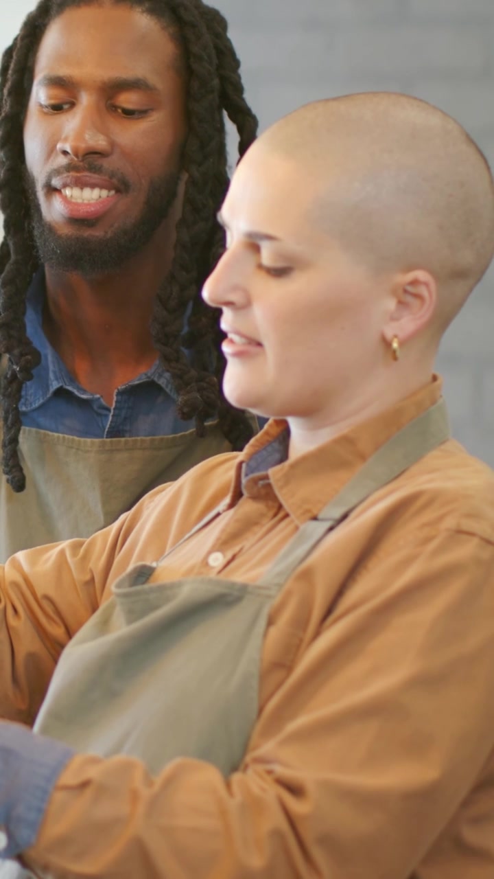 Video verticale: Posizionamento delle mani, lavoratore che inizia la preparazione al bancone, assistito da un collega, entrambi in grembiule.