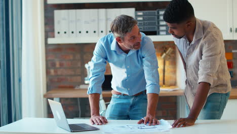 two male architects with laptop meeting and discussing building plans in modern office