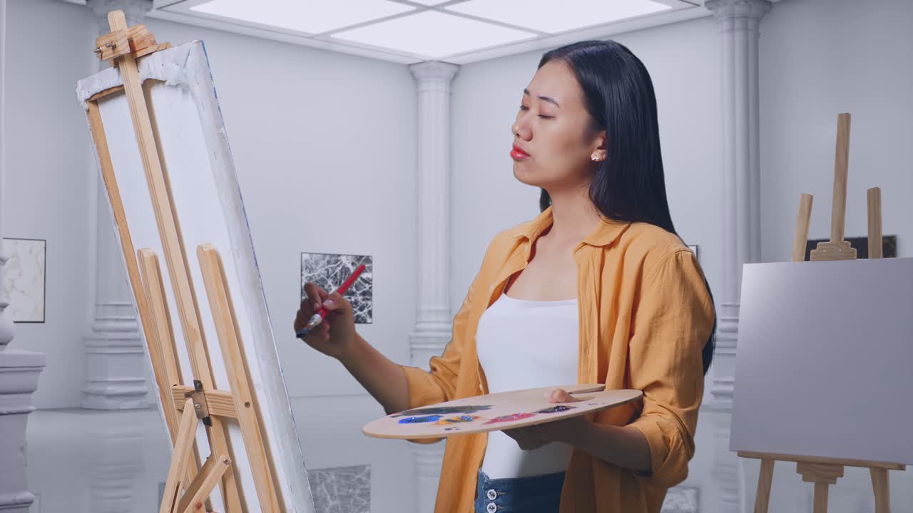 아시아 여성 예술가 가을 들고 갤러리에서 오일 페인트와 으로 캔버스에 그림을 그리는 동안 그림 개념에 대해 생각하고 있습니다.