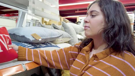 young woman choosing pillows in home goods store