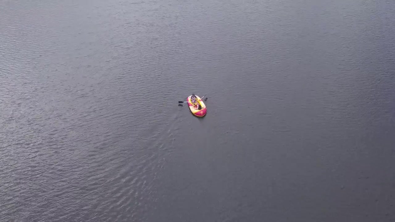 A lone kayak moves through expansive open water, captured from an aerial perspective. Ideal for themes of solitude and exploration.