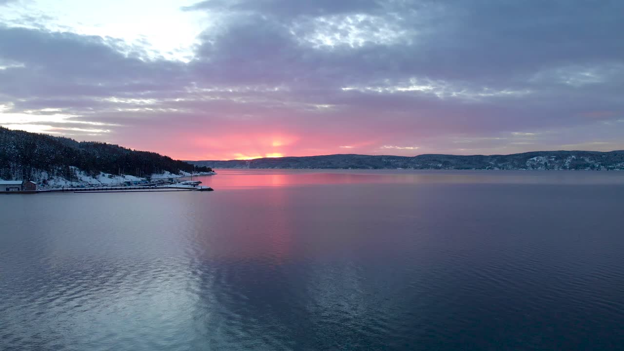 Forward aerial evening shot of Norwegian fjord with red sky
