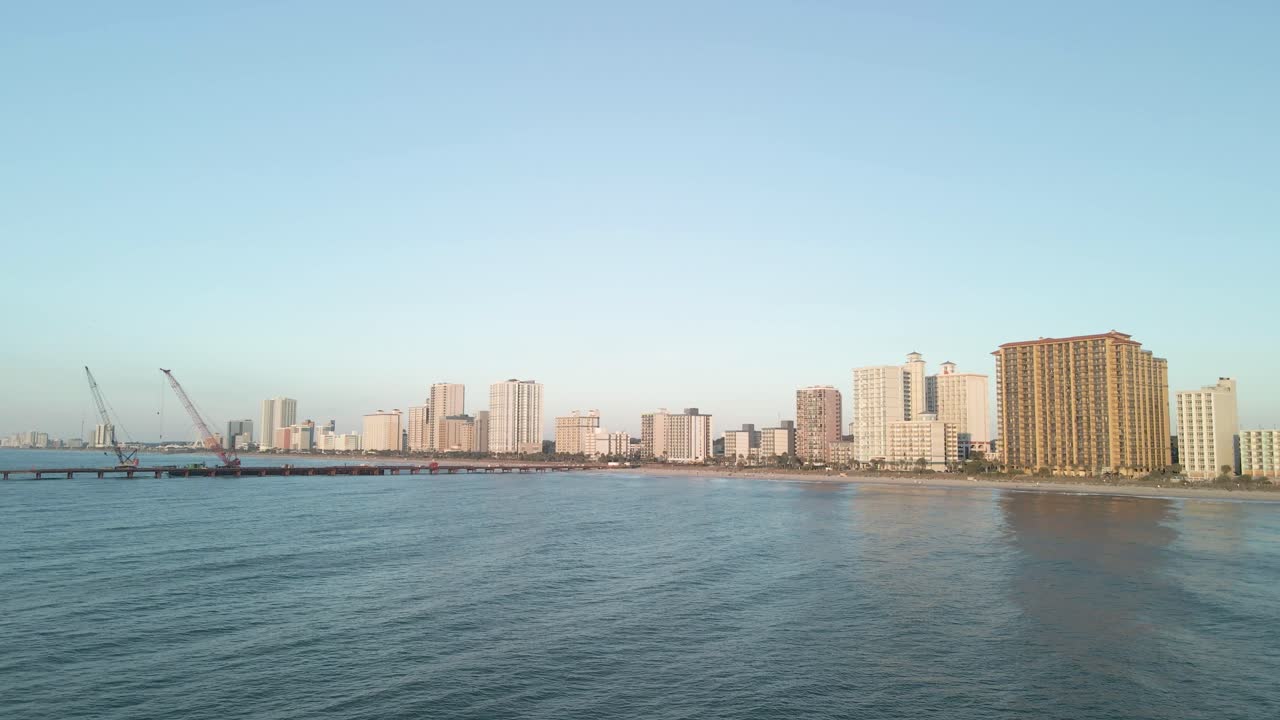 Aerial drone flying towards Myrtle Beach, South Carolina, beachfront skyline at sunrise