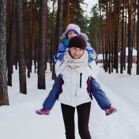 mother carries he daughter playfully through snowy woods