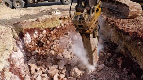 excavator at construction site digging on dusty ground with concrete debris