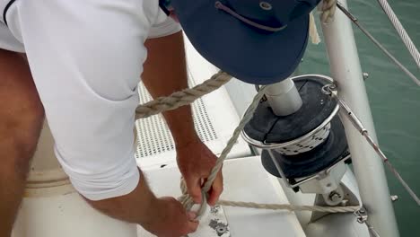 close up of a man tying an anchor rope on the cleat of a sailboat or catamaran