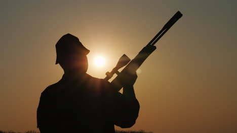 Silhouette-Eines-Jägers-Mit-Einer-Waffe,-Die-Sonnenstrahlen-Leuchten-In-Seinem-Gesicht