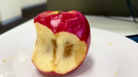 rotten bad apple - close side-on view more rotated - on a white plate
