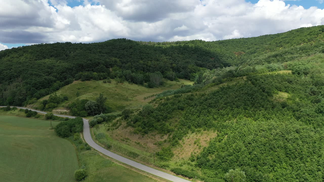 vista aérea de un coche conduciendo por una carretera rural en verano