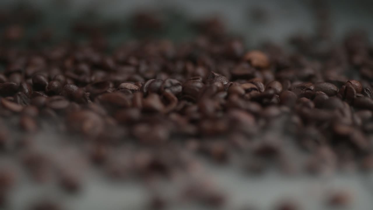 Close-up coffee beans falling, spilling onto the table into smoke, fog