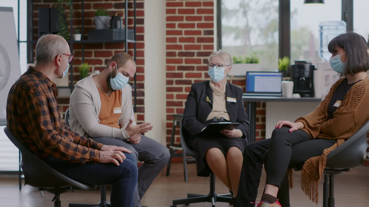 Senior man having conversation about addiction with group of people at aa meeting