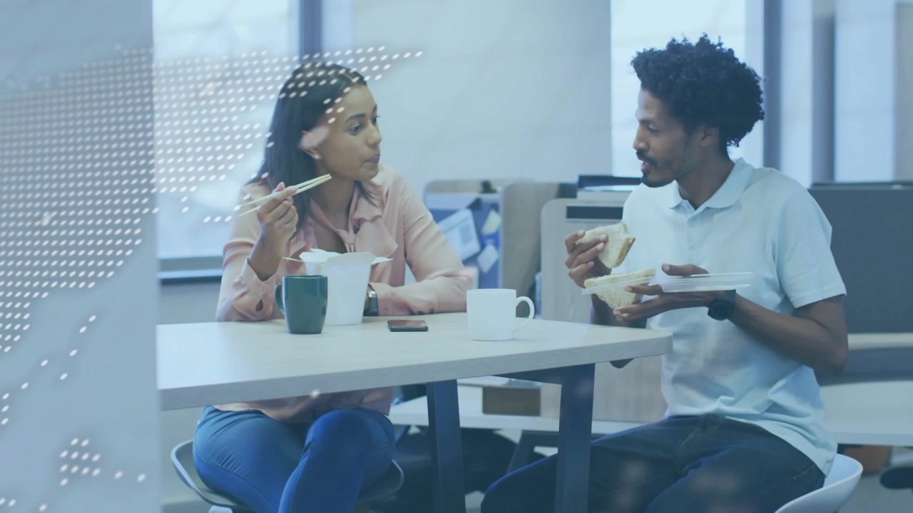 Two colleagues eating at business table, overlay fading and revealing smartphone during lunch chat