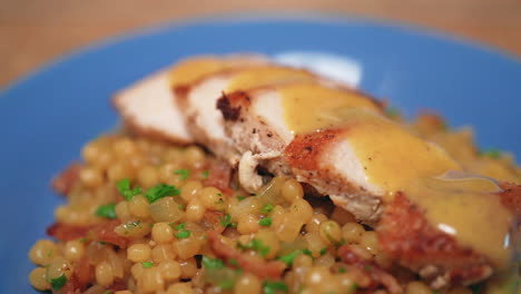 Maple-Dijon-chicken-breast-and-rich,-savory-gravy-on-a-bed-of-couscous---macro-view