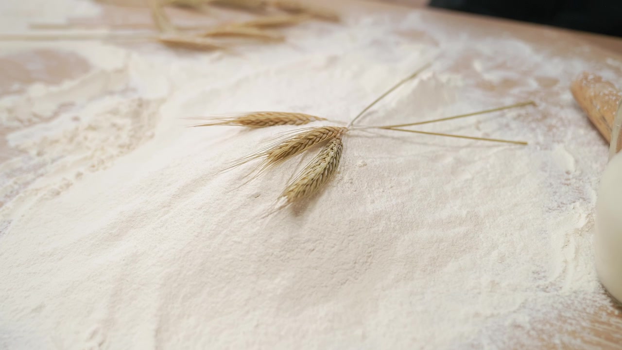 Spighe di grano che cadono su farina bianca su un tavolo di legno