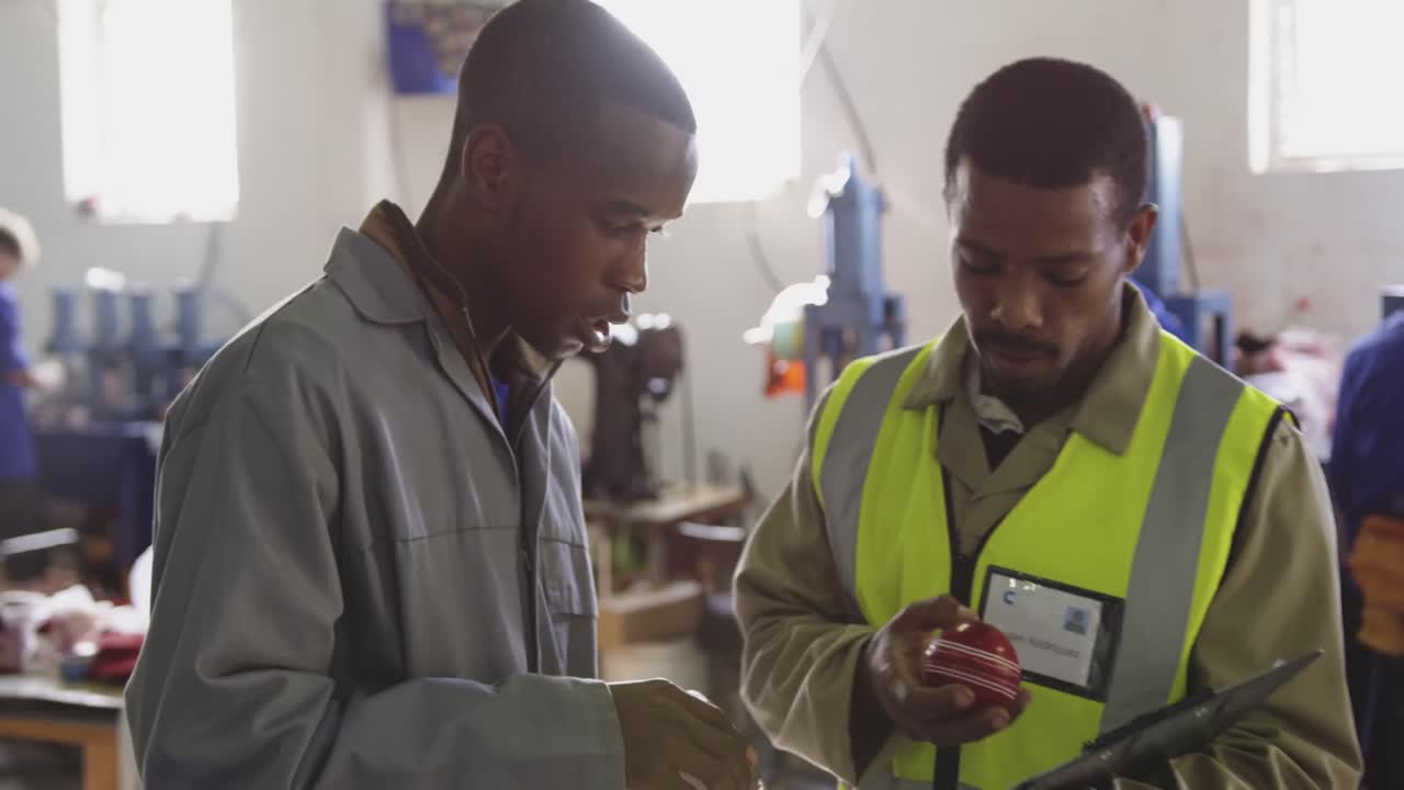 Colleagues checking quality cricket ball in factory