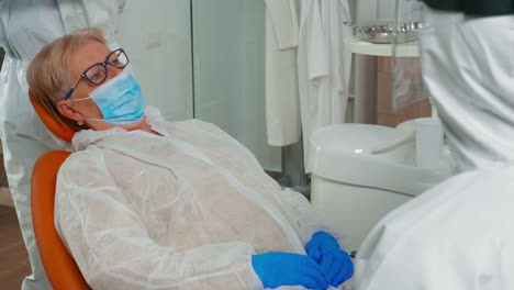 Patient-with-dental-bib-and-protection-mask-talking-with-doctor