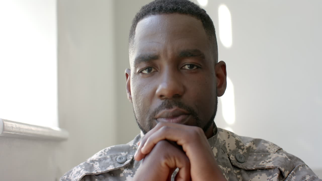 African American soldier in military uniform appears contemplative at home