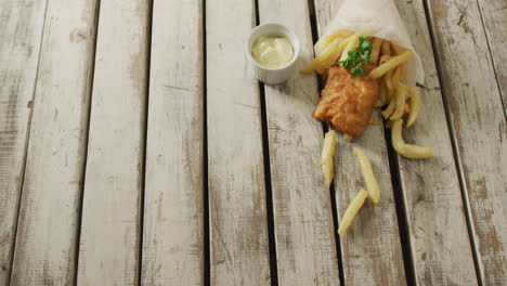 video of wrapped fish and chips with dip, on rustic table top with copy space