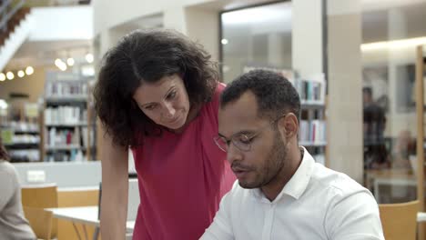 Cheerful-colleagues-communicating-at-library