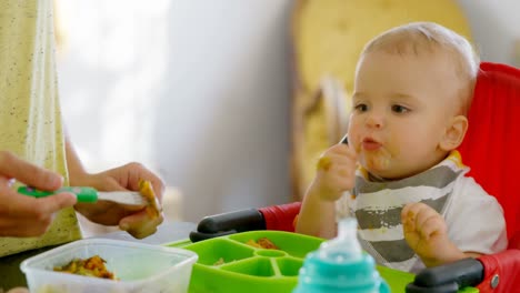 Mother-preparing-breakfast-for-her-baby-boy-in-kitchen-4k