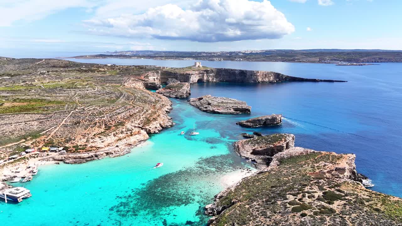 Den blå lagune i Comino, Għajnsielem, Gozo, Malta, med kalksteinsklipper og et grunt turkist basseng over karbonatbunnen mellom øyene Comino og Cominotto, klart middelhavs-droneflyvning fremover.