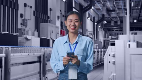 asian female with her smarphone with water production in bottling factory, she is looking at the camera with a smile