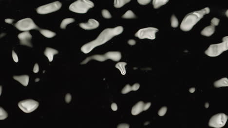 top-down macro shot of sporadic ripples on the surface of black fluid