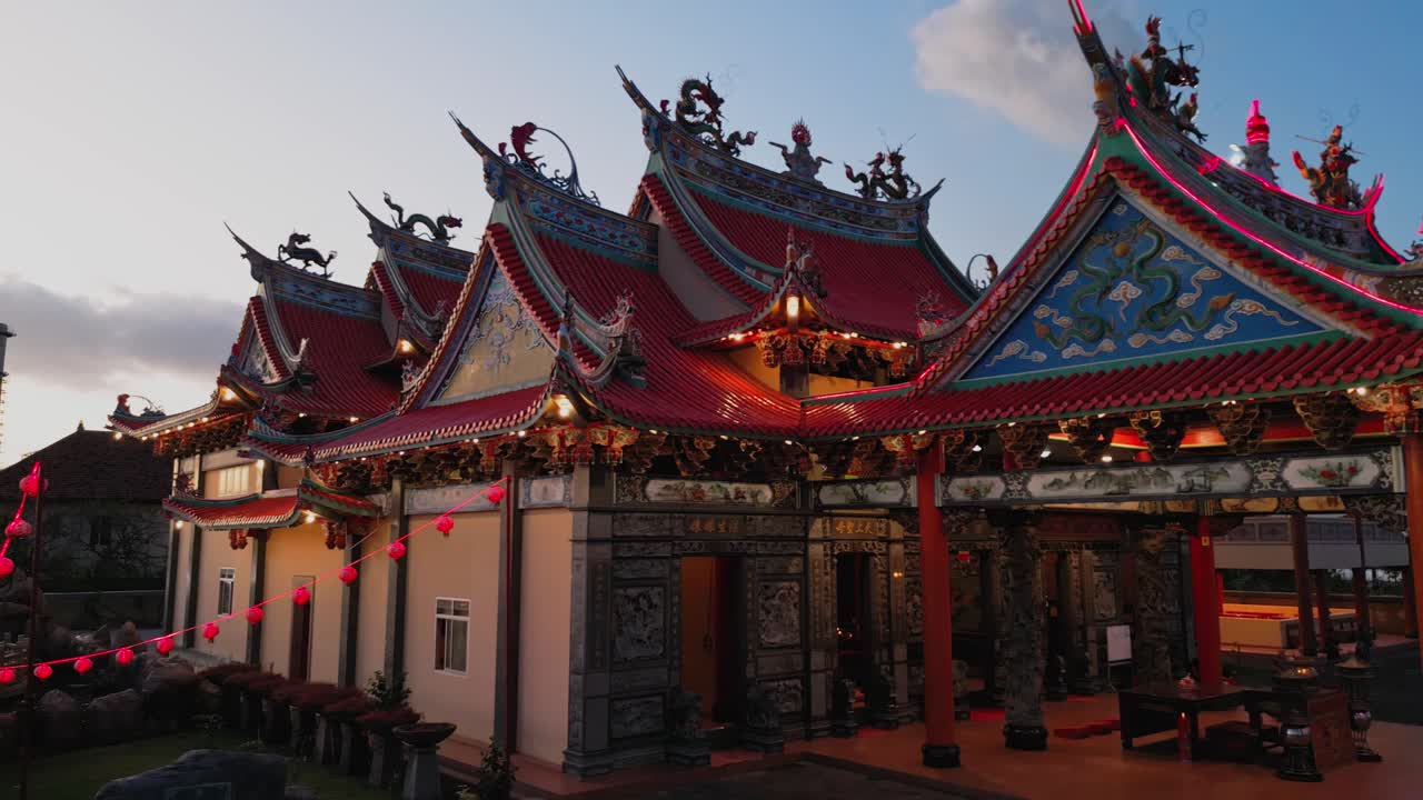 Captured by drone this sunset scene reveals a colorful Buddhist temple and a tall statue glowing against a beautiful sky filled with soft evening light