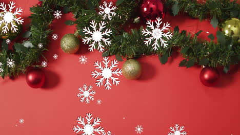 animation of snow falling over christmas decorations on red background