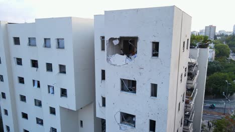circular drone close-up of missile impact hole in upper floor of residential building in north tel aviv