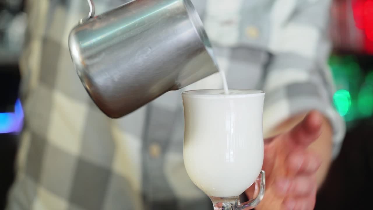Barista pours milk into a glass.