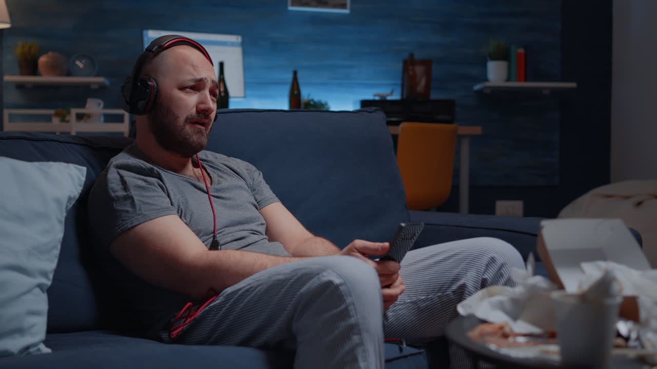 Trist, tankefull og engstelig mann som lytter til musikk med smarttelefonen