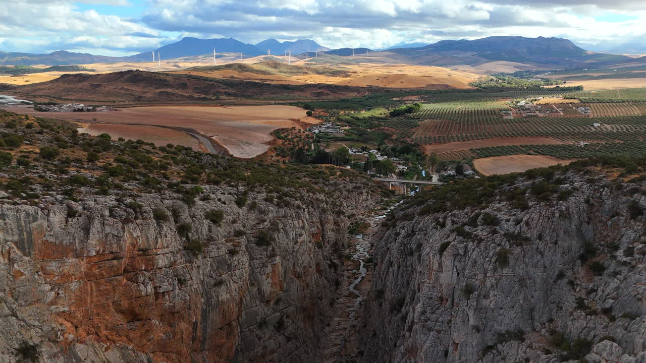 Arco di drone cinematografico attorno a un affioramento roccioso isolato nella catena della Sierra Morena — la telecamera che orbita lentamente mentre la valle retrostante riempie l'inquadratura, evocando grandezza e solitudine.