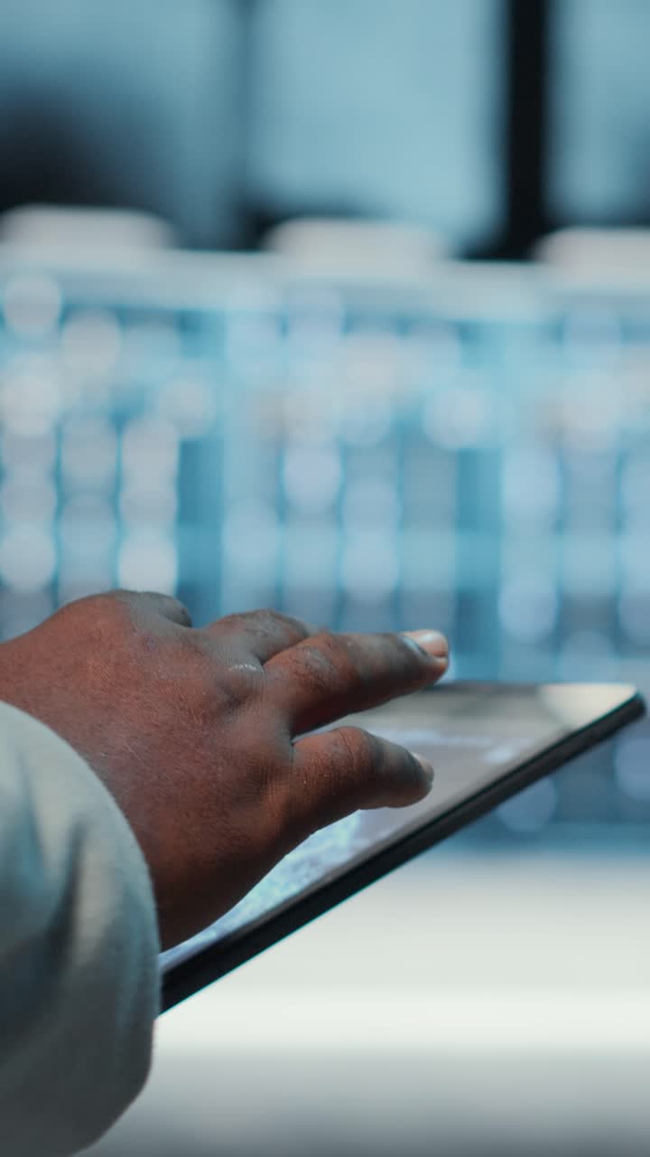 Vertical video Manager walking in server hub using tablet to find firewall misconfigurations