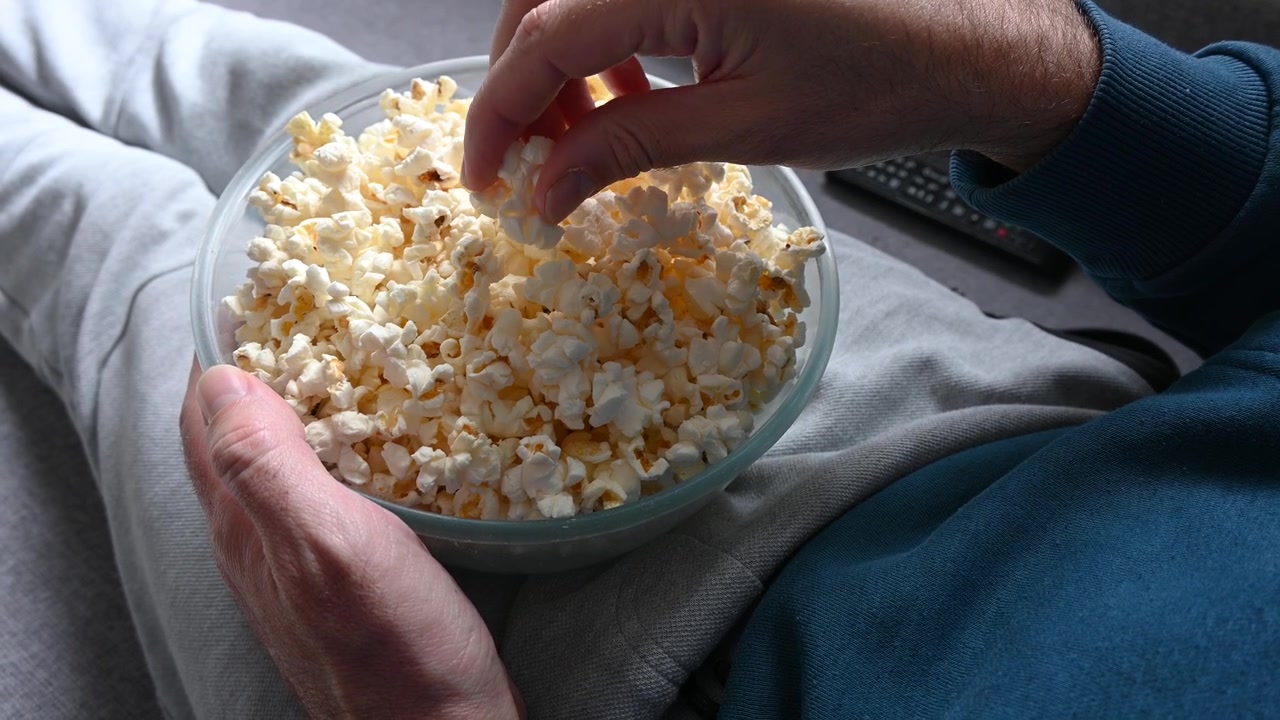 Uomo che mangia popcorn sul divano